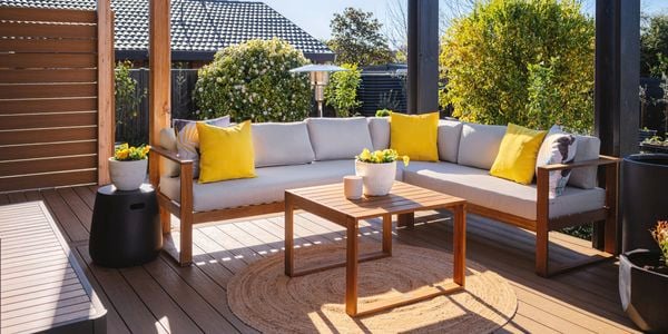 Outdoor l shaped couch with cream and yellow cushions on display