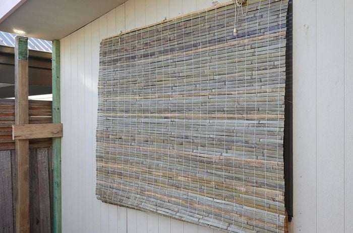 A bamboo blind covering a window on the outside of a house
