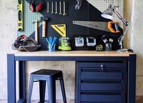 DIY Tools station with many tools attached to a wooden board and chair in front of it.