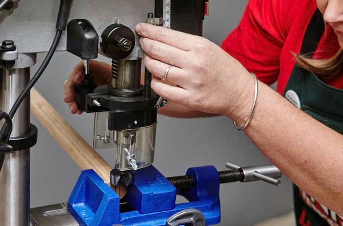 Person clamping timber dowel in place, ready for cutting.