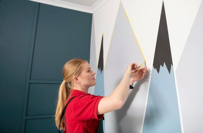 Person peeling tape lines off wall.