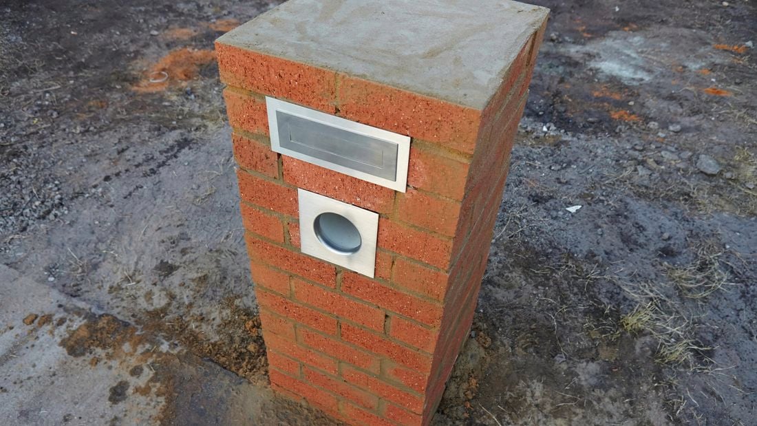 A finished brick letterbox at the edge of a lawn
