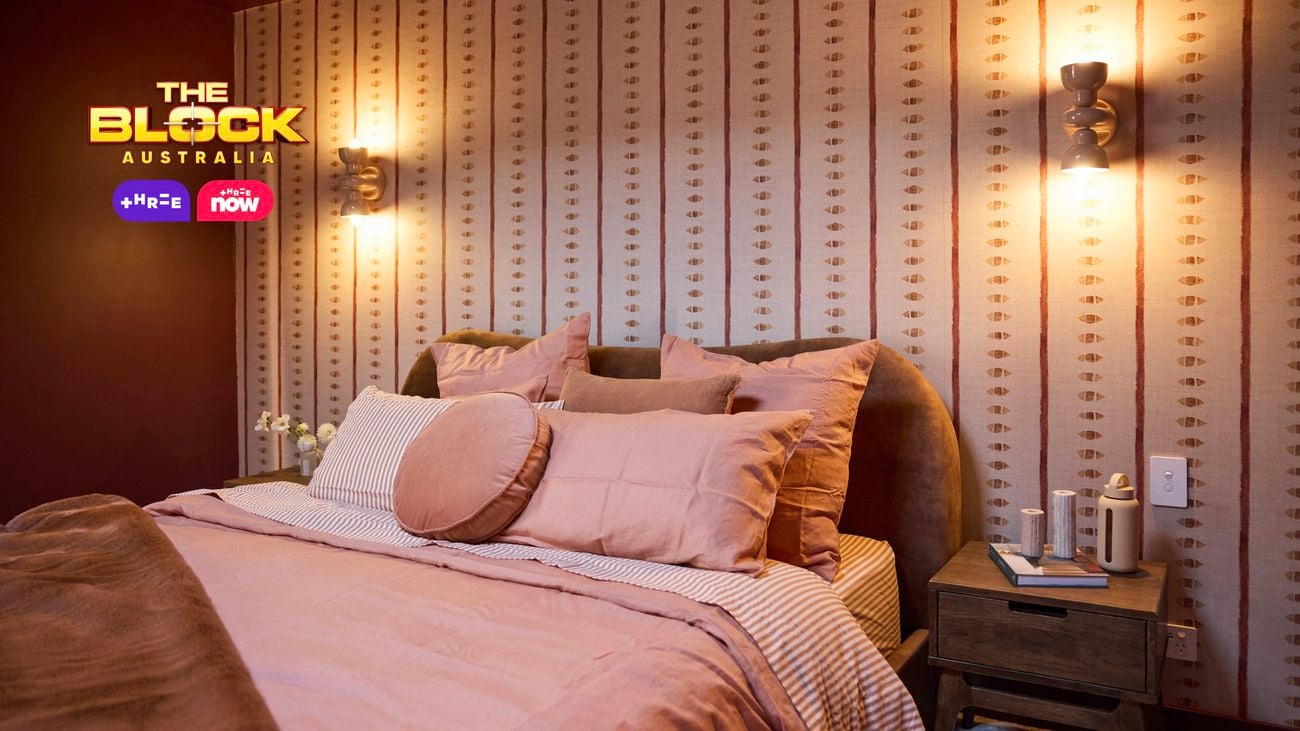  Close-up of bed with curved headboard, warm lighting, and red tones.