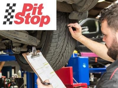 mechanic reviewing car tyres while car is on a hoist.