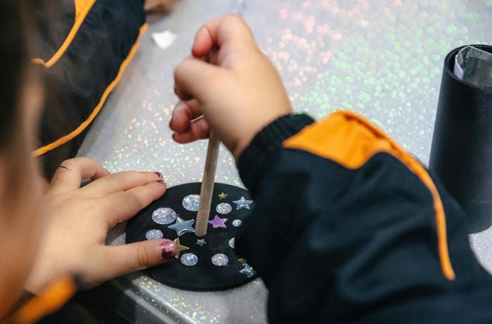 A length of wooden dowel being applied to a circular coaster decorated with stars
