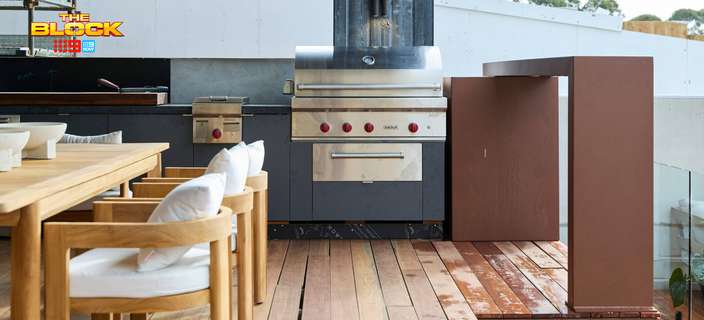Outdoor kitchen and dining area featuring timber decking, a built-in barbecue, timber furniture and glass balustrade.
