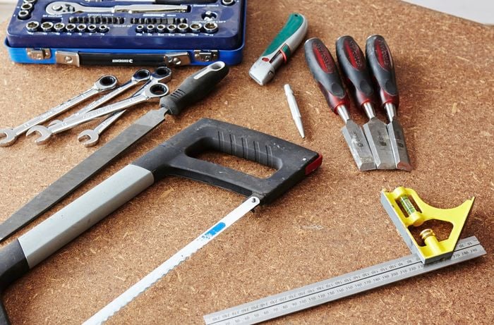 A square rule, saw, chisels, spanners and boxcutter