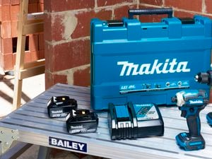 A set of Makita tools sitting on a ladder inside a house being constructed.