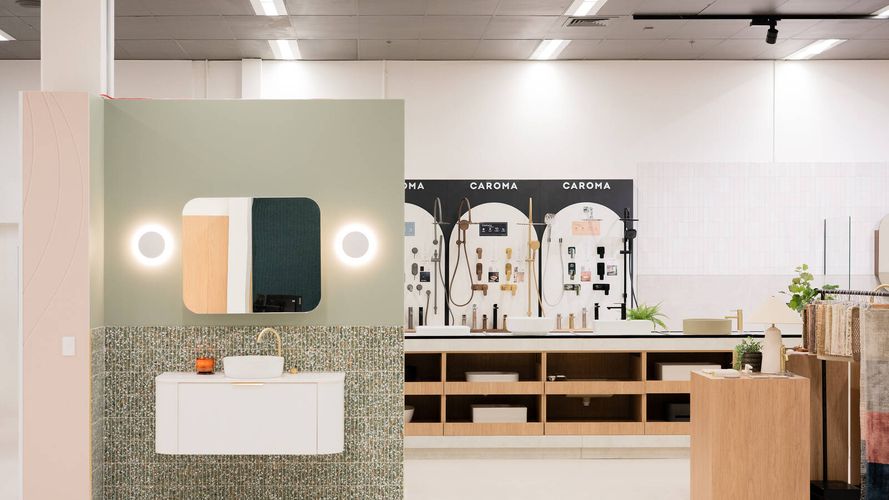 Bathroom showroom display featuring a floating vanity, illuminated mirror, mosaic wall tiles and a Caroma tapware selection wall.