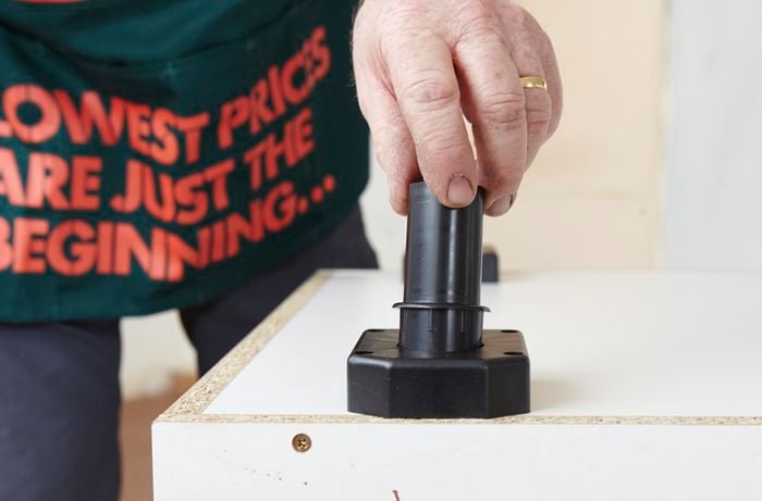 A person inserting a tube into a base plate for an adjustable foot 