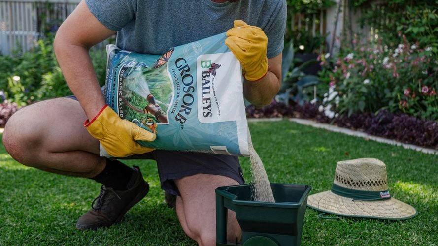 Person pouring grosorb into a spreader.