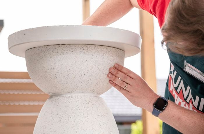 A person securing the paver to the pot.