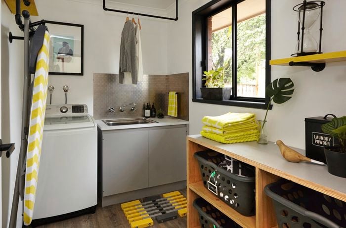 The renovate laundry with a washing machine, ironing board, hanging clothes and towels.