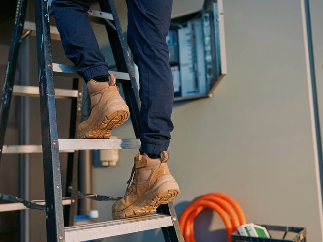 A person climbing up a ladder at a constructions site.