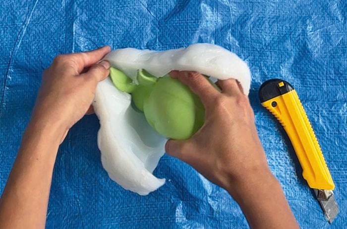 Blue tarp sitting on a table - person pulling apart white mould to see a white decorative rabbit