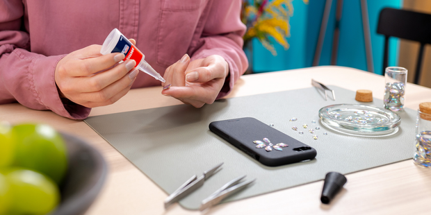 Applying precision adhesive to decorative gems during a mobile phone case craft project