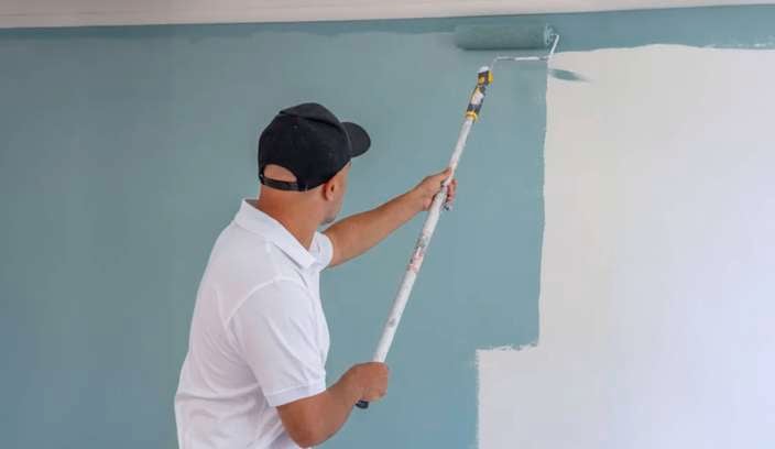 Person painting an inside wall with a roller