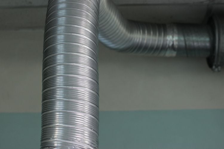 Flexible aluminium duct run through a roof cavity, connected between joists.