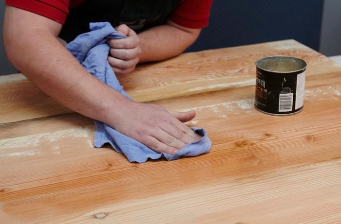 An assembled tabletop being waxed with a rag by a Bunnings team member