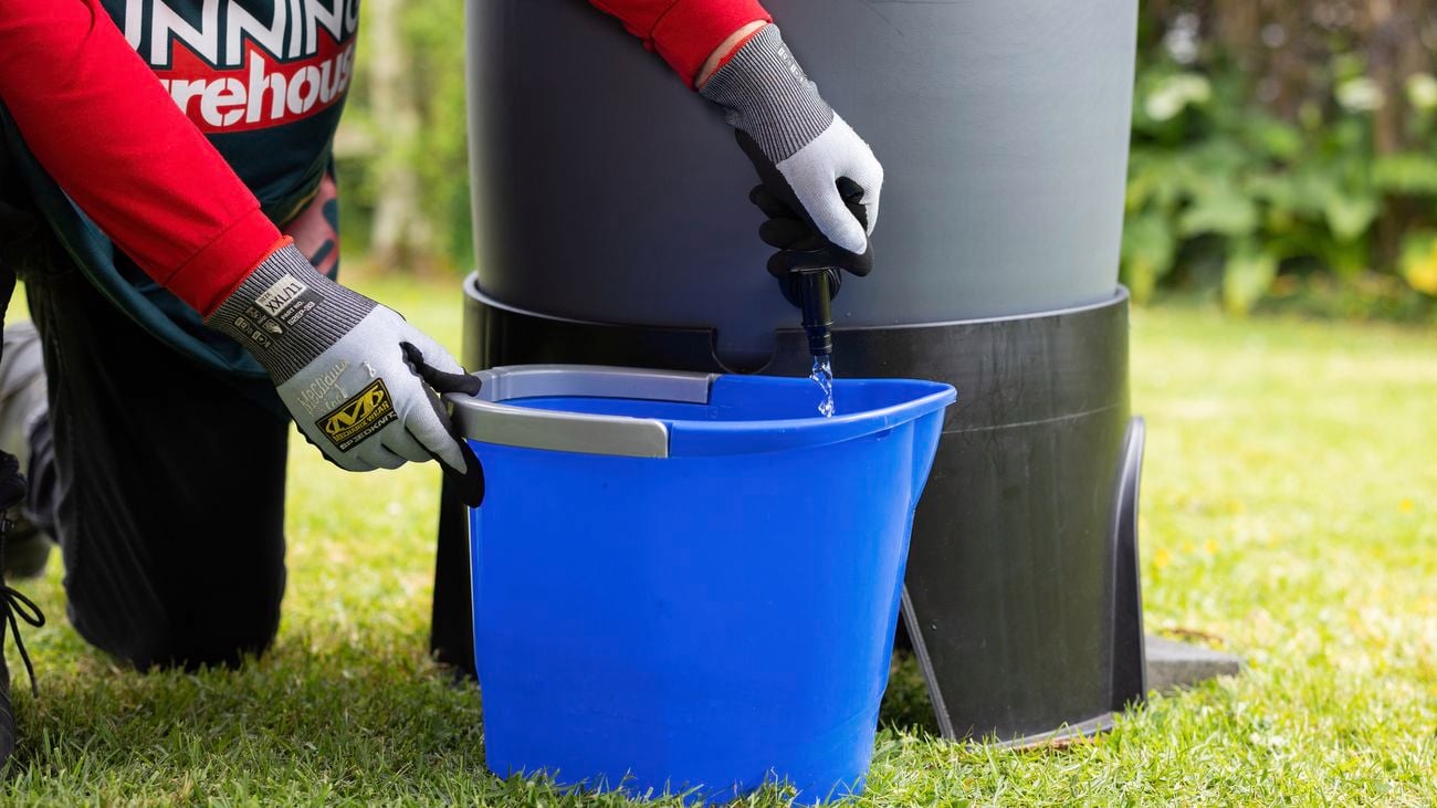 Bunnings employee turns tap to let water run from rainwater tank into blue bucket