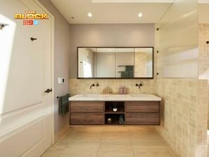Modern bathroom with double sink vanity, large mirror, light tiles, glass shower partition, and white door with black hardware. 