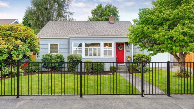 Front of a cottage house with front garden and fencing.