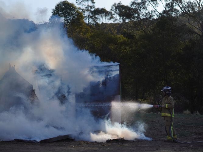 Extinguishing the smouldering untreated timber hut.
