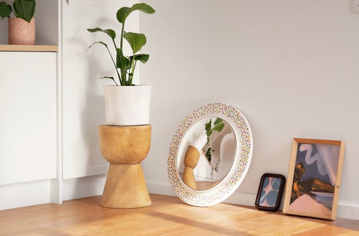 A round decorative mirror and framed artwork have been removed from the wall and placed nearby, making it easy to update the room or create a new wall arrangement. 