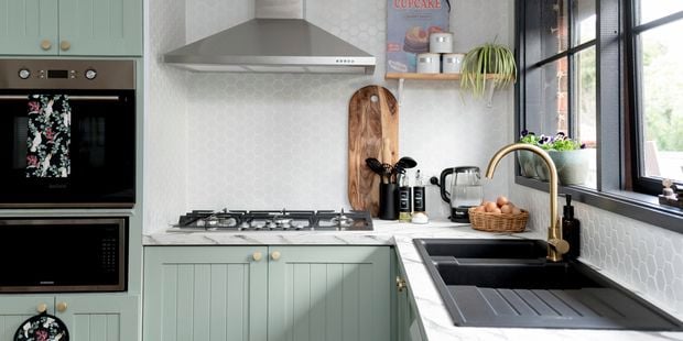 Kitchen with green cabinets and marble benchtops.