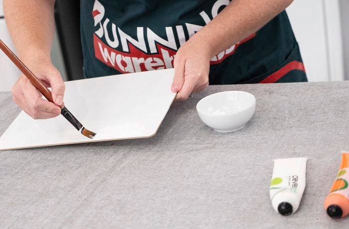 A flat game board being painted with a base coat of white