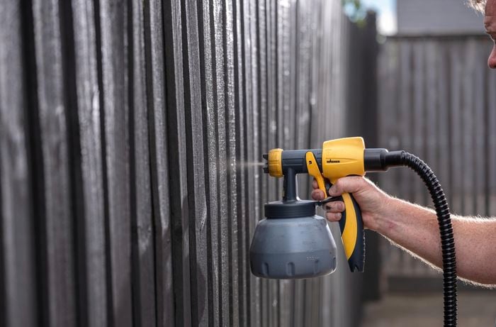 A Bunnings team member applying the second paint coat using a spray gun.