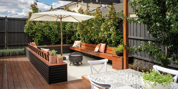 Outdoor lounge with four white chairs, a table and a BBQ next to it.