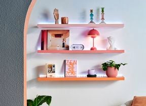 Floating shelves seen through an archway lit up with LED lights and topped with books and decor