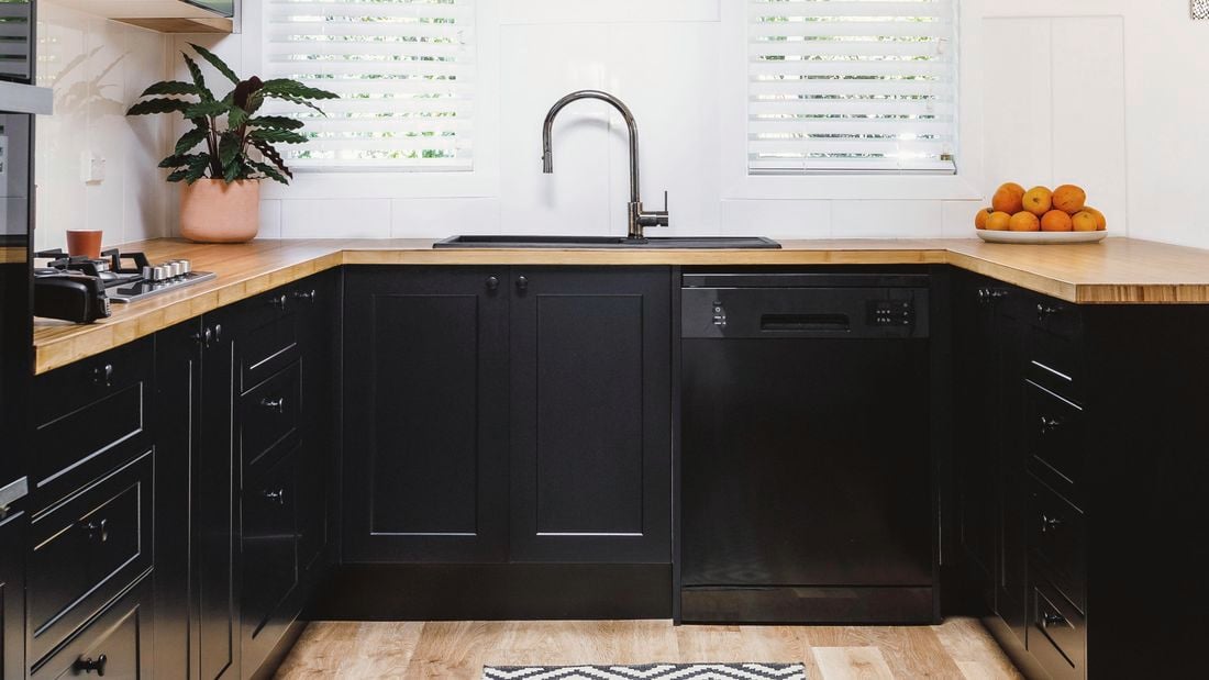 kitchen with black cabinets and appliances, white walls and plantain shutters