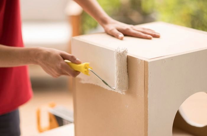 A person is using a paint roller to paint the boxes.