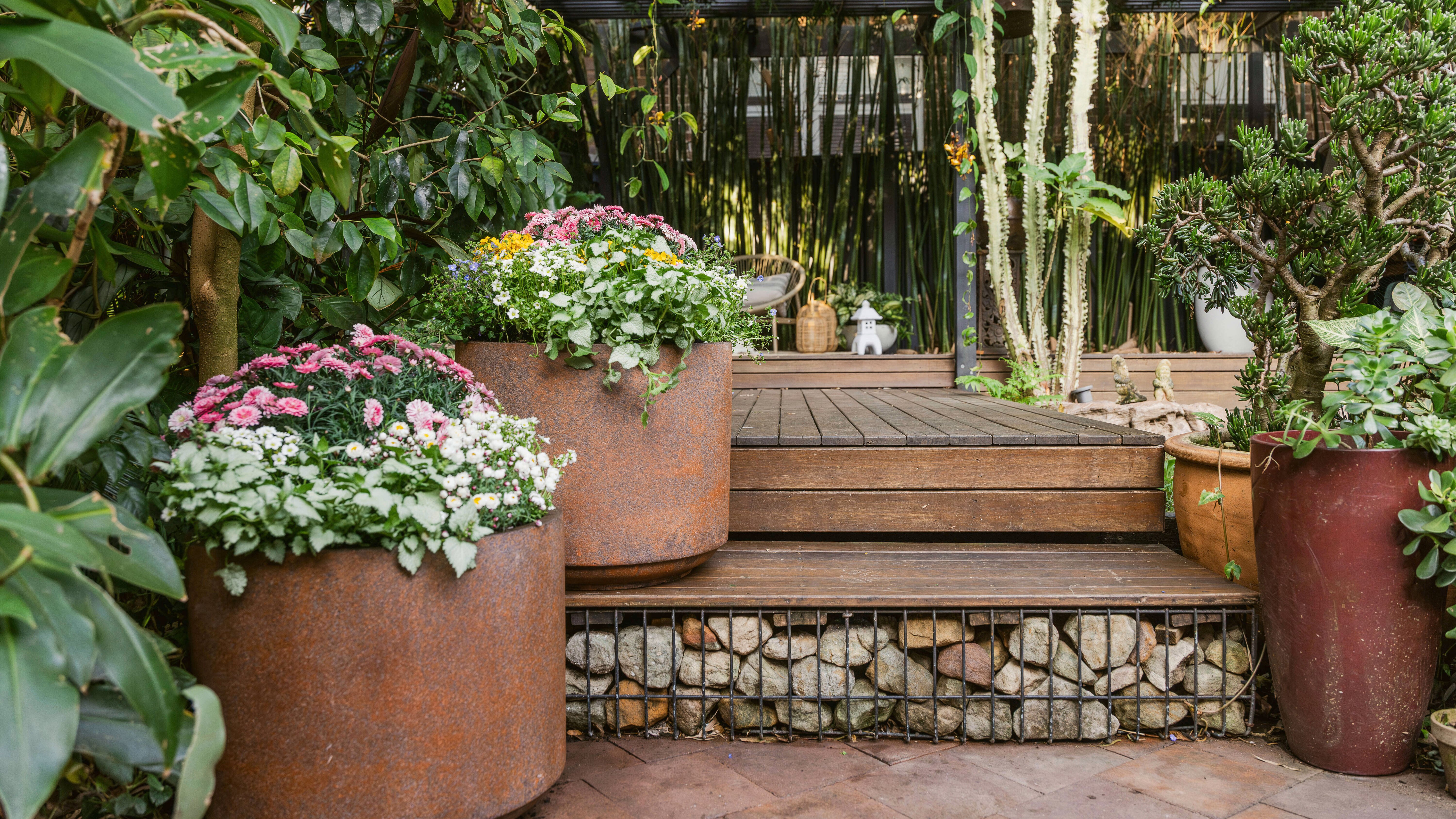 Timber steps with stones and large rustic pots with flowers.