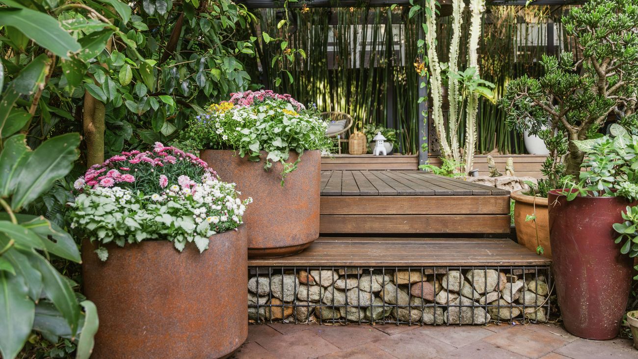 Timber steps with stones and large rustic pots with flowers.