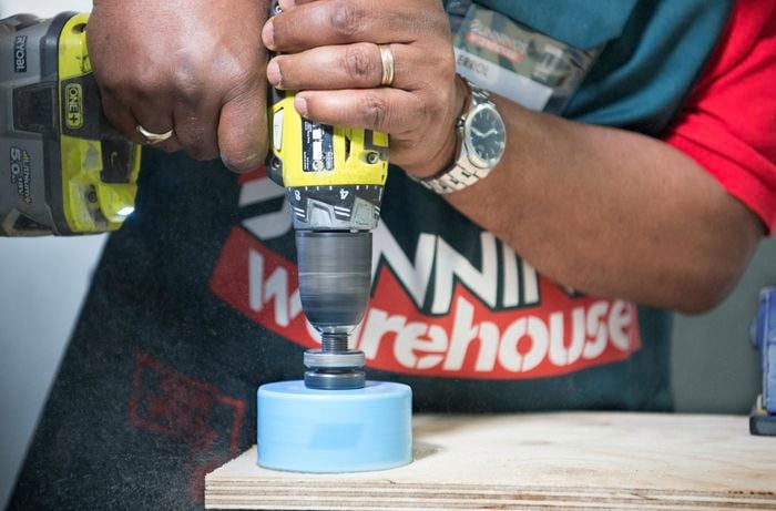 A person drilling a countersink hole in a plywood circle