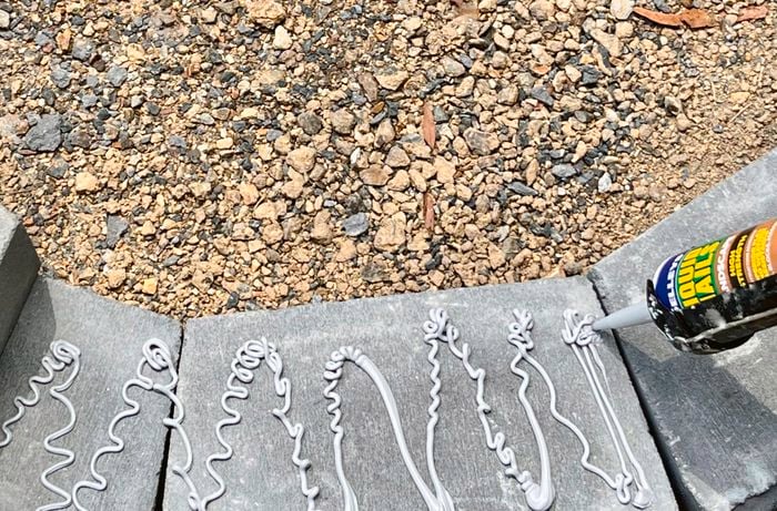 A person applies landscaping adhesive to retaining wall blocks