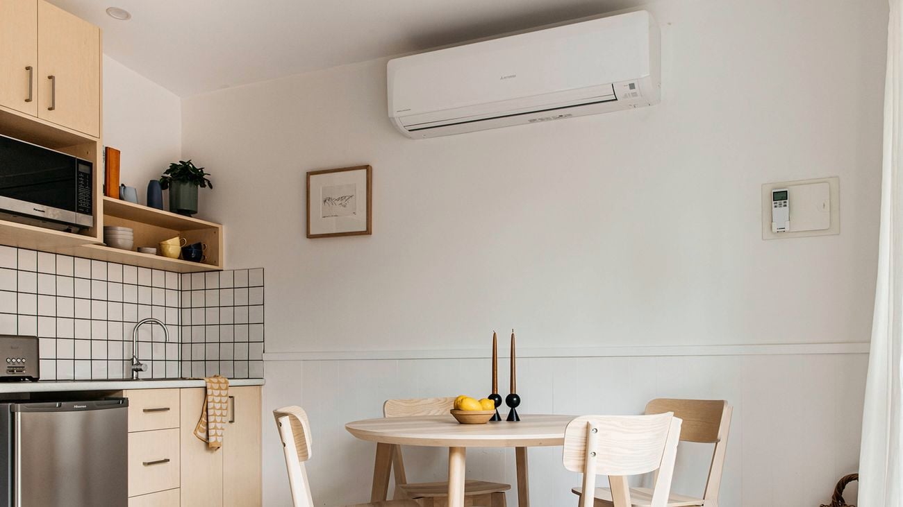 A corner of a kitchen, with a small table and chairs and air conditione