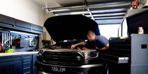 man fixing car in a garage with black tool workshop and tool box in the background