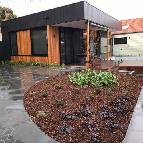Entrance to home with concrete driveway and woodchip garden