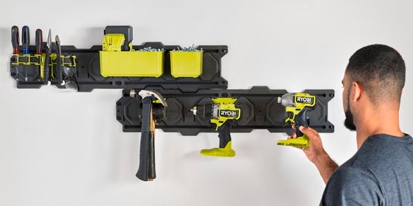 A man hanging an impact driver onto a hook secured to a LINK wall plate.