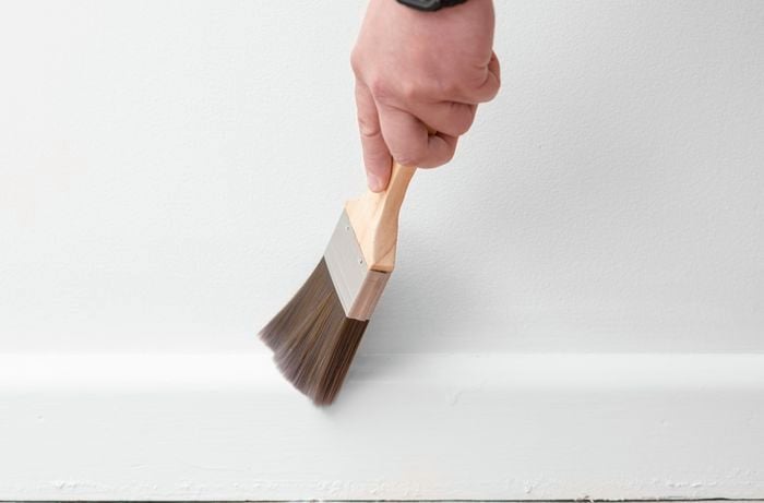Dusting off the skirting board with a paint brush