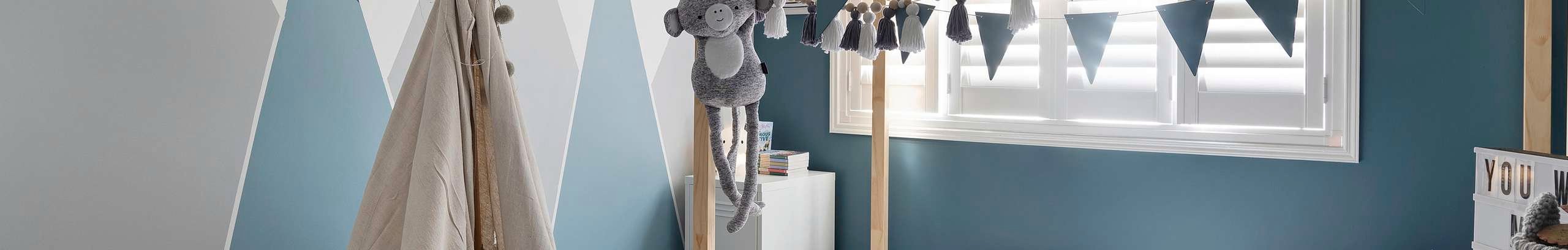 Kids bedroom with timber bed frame, bunting, play tent and toys.