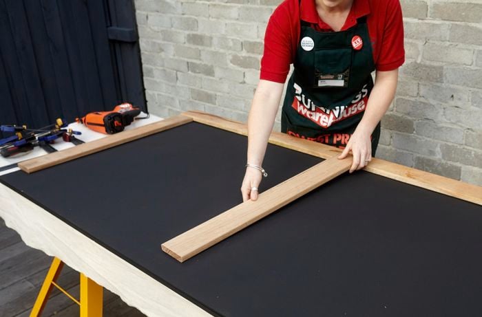 Person attaching frame to chalkboard.