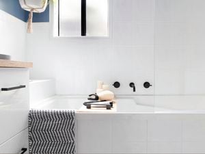 White bath in a bathroom with a towel draped over the side.