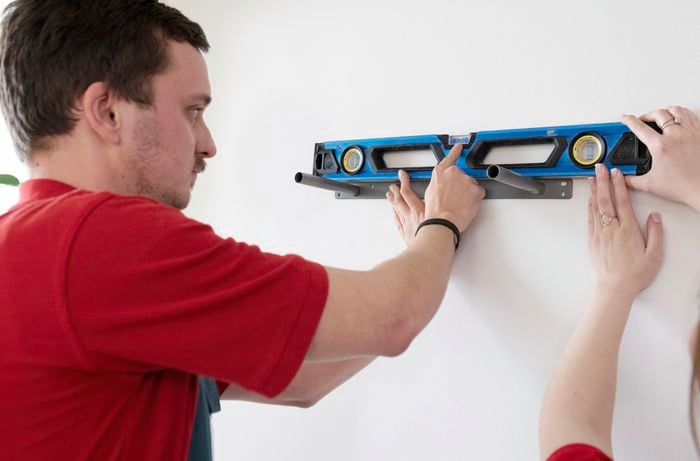 A spirit level being used to align floating shelf supports