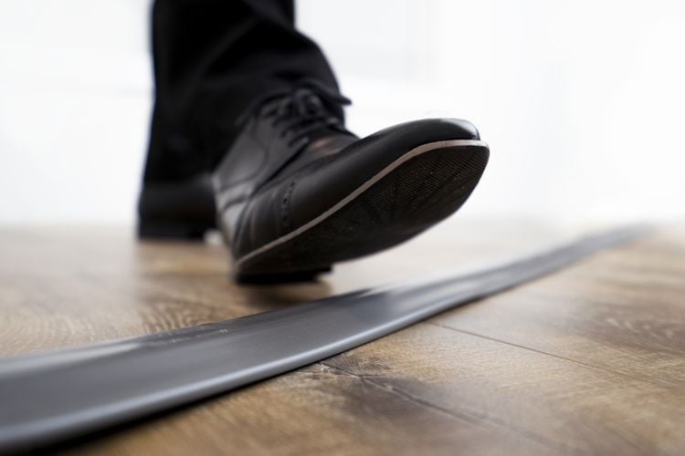 Close up of person's shoe stepping on flat conduit used to hide power cables