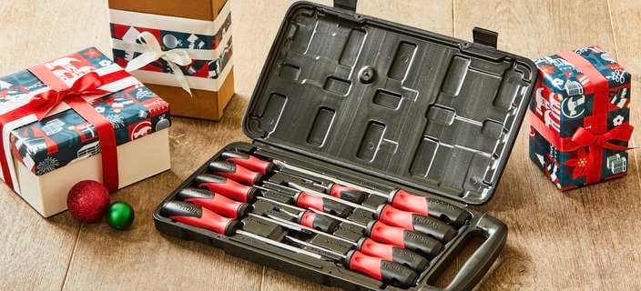 An open Trojan screwdriver set on the floor next to Christmas gifts.